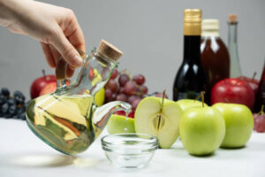 Hand Pouring A Jug Of Apple Cider Vinegar Into A Bowl