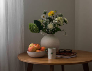 Vase Of Flowers And A Bowl Of Apples Atop A Table