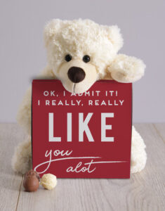 White teddy bear holding a box of chocolates