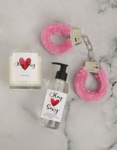 Massage oil, scented candle and pink fluffy handcuffs