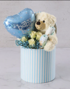 Cream teddy bear with cream roses and blue balloon in a hat box. 