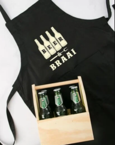 A black apron with the words, "Beer and braai", and a wooden crate filled with bottles of Castle Lite.
